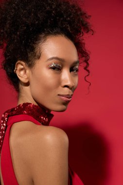 Genç bir kadın zarafetini ve büyüleyici gülümsemesini parlak kırmızı bir elbiseyle sergiliyor..