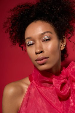 Bir kadın parıltılı makyajla ve zarif bir kıyafetle ışıldar, neşe saçar..