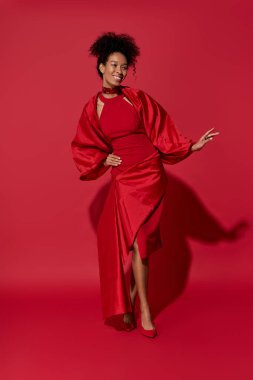 Işıldayan mutluluk, genç bir kadın çarpıcı kırmızı bir elbise içinde, zarafet ve zarafet sergiliyor..