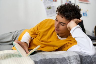 Tarz sahibi bir genç evinde rahat bir şekilde rahat bir yatakta kitaplara dalmış, huzurlu bir anın tadını çıkarıyor..