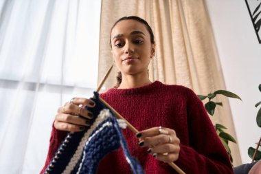 Genç bir Afrikalı Amerikalı kadın kışın modern dairesinde örgü örmekten hoşlanır..