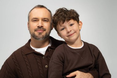 Mutlu bir baba oğlunu kucaklıyor, hem sıcak kazaklar içinde, huzurlu bir ortamda gülümsüyor..
