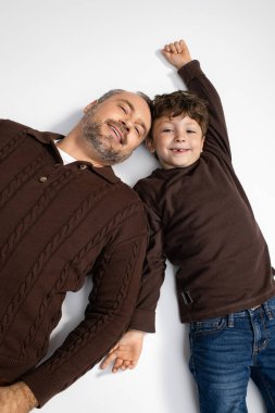 Bir baba, gülümseyen oğlunun yanında yatar. Birlikte eğlenceli ve sevgi dolu bir anın tadını çıkarır..