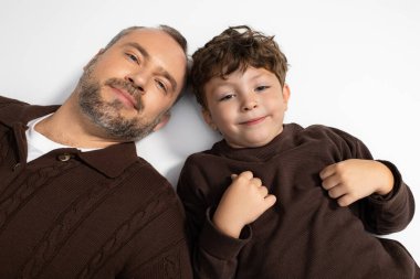 Bir baba ve küçük oğlu evde eğlenerek vakit geçiriyorlar, sıcak bir şekilde gülüyorlar..