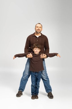 Neşeli bir baba, sakin bir stüdyo ortamında neşeli bir bağ sergileyerek küçük oğlunu kucaklıyor..