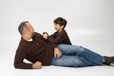 Neşeli bir baba ve küçük oğlu neşeli bir anı paylaşıyorlar, evde gülüyorlar ve yakınlaşıyorlar..