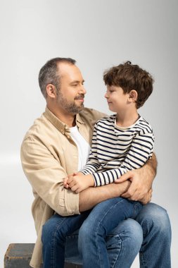 Bir adam oğlunu kucaklarken gülüşleri ve sıcaklıkları birlikte neşeli bir anda paylaşır..