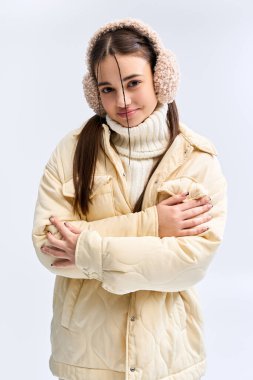 Genç bir kız şık bir kışlık ceketin içinde sıcak bir poz veriyor, içeride kış havasını kucaklıyor..