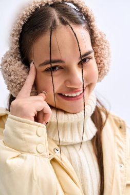 Güzel genç kız şık bir kışlık ceket ve kulaklık giyer, kışın neşe saçar..