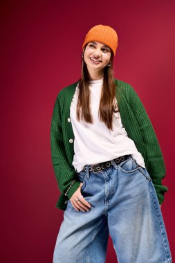 Modayı takip eden gençler, kışın rahat bereler ve büyük boy kotlarla kırmızı arka planda eğleniyorlar..