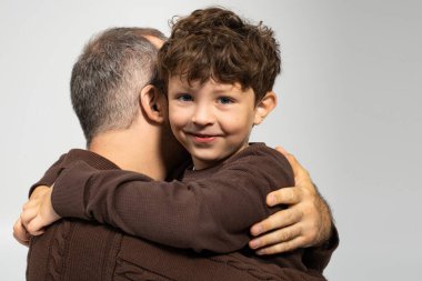Sevgi dolu bir baba, genç oğlunu sıkıca tutar. Yürekten bir anı paylaşırlar..