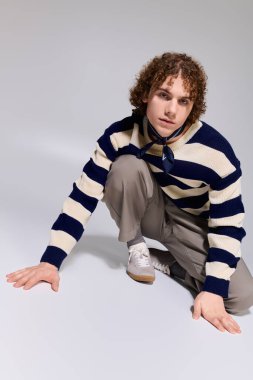 Şık giyinen genç, hareketli ve kendine güvenen bir duruş sergiliyor..