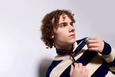 Genç, gösterişli pozlar veriyor, şık bir kıyafet giyiyor ve şık bir stüdyoda büyüleyici bir tavır sergiliyor..