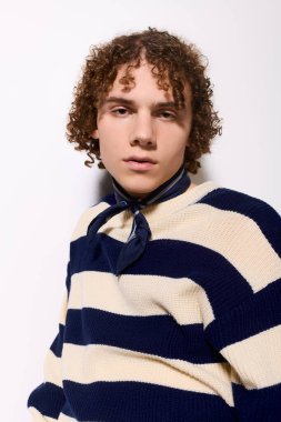 Modern bir ortamda kıvırcık saçlar ve kalın çizgilerle dinamik bir poz veren modaya uygun bir genç..