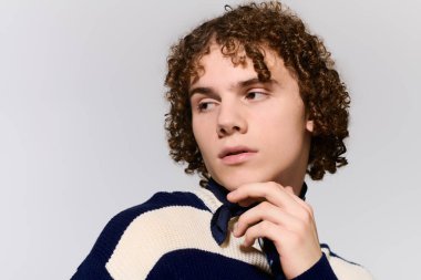 Kıvırcık saçlı ergen, modaya uygun kıyafetler ve basit bir arkaplana karşı aktif pozlar sergiliyor..