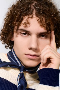 Modayı takip eden bir genç, oyuncu ve büyüleyici bir ifadeyle çarpıcı bir kıyafetle güven içinde poz verir..