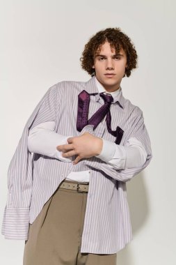 Genç, gösterişli pozlar veriyor, sıradan ve resmi unsurları çarpıcı bir kıyafetle birleştiriyor..