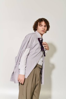 Genç, kendine güvenen bir şekilde şık bir kıyafetle poz veriyor. Moda ve gençlik enerjisinin bir karışımını sergiliyor..