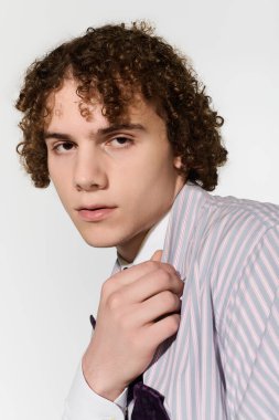 Kıvırcık saçlı ergen, kendine güvenen bir şekilde şık bir kıyafetin içinde genç enerjisi yayıyor..