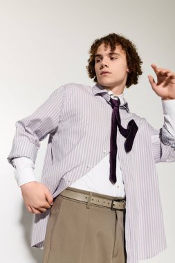 Şık bir genç, kendine güvenen bir ifadeyle poz verir, benzersiz moda tercihleri sergiler..