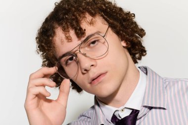 Kıvırcık saçlı ve gözlüklü ergen, modaya uygun giyinip poz vererek bireyselliğini ifade ediyor..