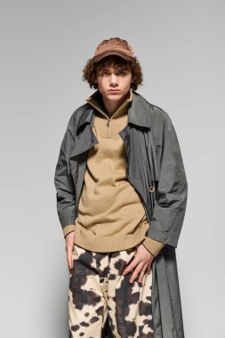 Genç, basit bir arka plana karşı şık bir pozla cesur bir poz veriyor..