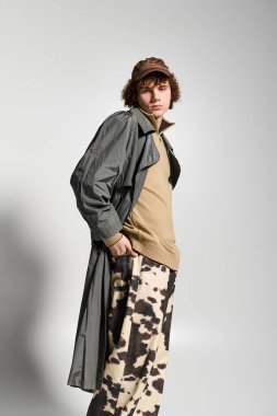 Genç, özgün bir stil sergiliyor, pürüzsüz bir arkaplana güvenle poz veriyor..