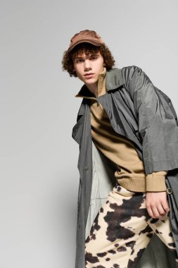 Genç, basit bir arkaplana karşı aktif bir poz verirken eşsiz bir tarzı benimsiyor.