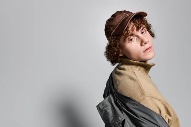 Moda çağındaki genç aktif bir şekilde poz veriyor. Moda kıyafetinin içinde kendine güven ve tarz yayıyor..