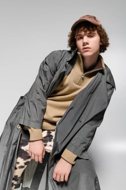 Modayı takip eden genç, basit bir arkaplana karşı şık kıyafetler içinde cesur bir poz veriyor..