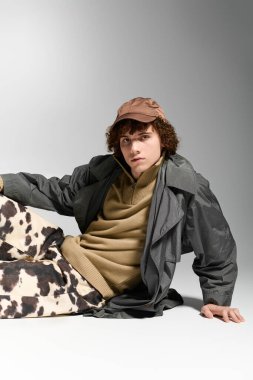 Şık bir genç, enerjik bir moda ve kendine güvenen bir tavırla yere eğiliyor..