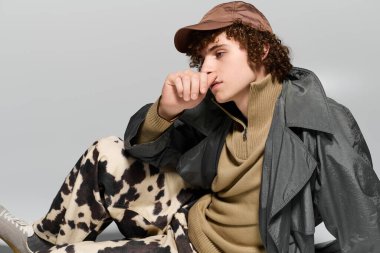 Ergen kendine güvenerek poz veriyor, moda kıyafetleri ve evde otururken neşeli tavırları vurguluyor.