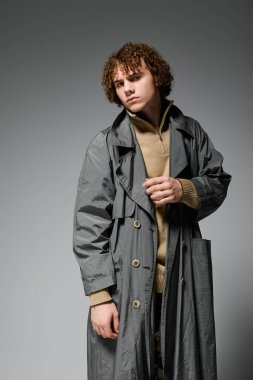 Genç aktif olarak parlak gri bir ceketle poz veriyor. Moda tarzı ve eşsiz enerjisiyle dikkat çekiyor..