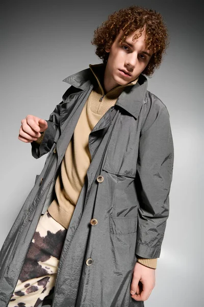 Modern kıyafetler ve şık bir palto giyen şık bir gencin dinamik pozu..