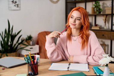 Canlı kızıl saçlı genç bir kadın, sıcaklıkla çevrili defterine yazarken yansıyor..