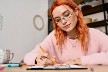 Şık dairesinde rahat bir şekilde otururken kızıl saçlı neşeli bir kadın eskizler çiziyor..