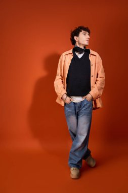 Şık bir adam canlı turuncu bir duvara karşı durarak modern bir cazibe yayıyor..