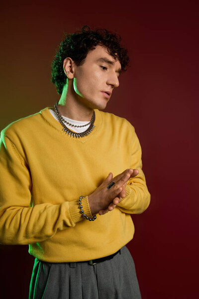 Confident man in trendy yellow outfit poses thoughtfully against a colorful background.