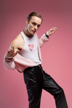 Bir adam neşeli bir ruh ve gurur sergiliyor, pembe temalı bir ortamda zevkle poz veriyor..