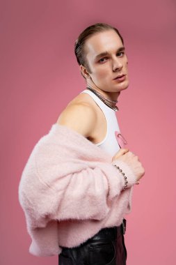 Genç bir adam cesur bir moda sergiliyor. Aşkı parlak, pembe bir arka planda kucaklıyor..