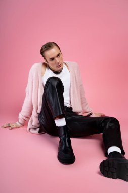 Bir adam eşsiz bir sevgililer günü pozu verir pembe bir arka plana karşı.