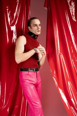 Kendine güvenen bir adam, neşeli bir ortamda canlı kırmızı ve pembe elbiseler sergileyen Sevgililer Günü 'nü kucaklıyor..