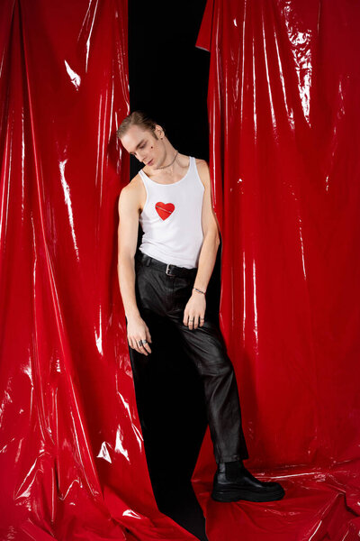 A man stands confidently in a heart themed outfit, embracing queer love during Valentines Day.