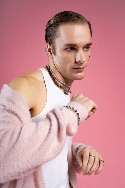 A stylish man confidently poses against a pink backdrop, celebrating love and identity.
