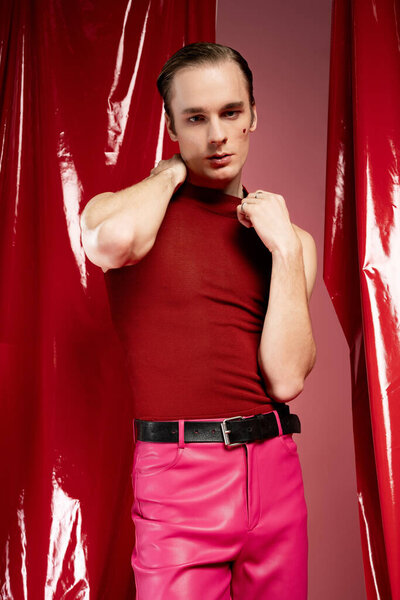 A man in bold red and pink poses confidently against a vibrant backdrop, embodying love.
