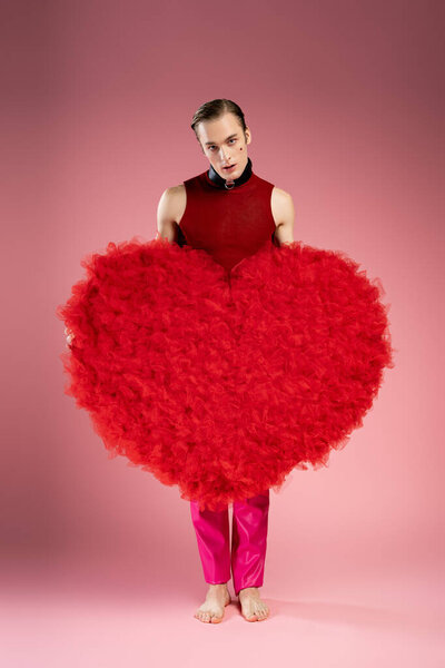 A man displays his heart themed outfit at a joyful Valentines Day celebration.