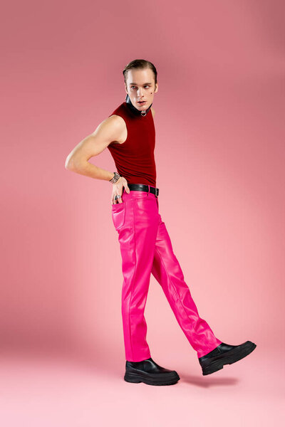A confident man showcases bold pink attire while embodying joy and love in a cozy setting.