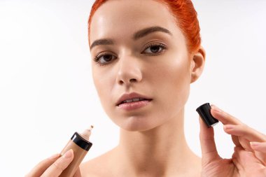 Güzel bir kadın makyaj rutinini sergiliyor. Temeli parlak ve temiz bir ortamda tutuyor..