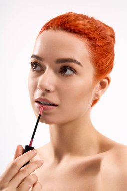 Genç, güzel bir kadın canlı dudak parlatıcısıyla görünüşünü güzelleştiriyor..