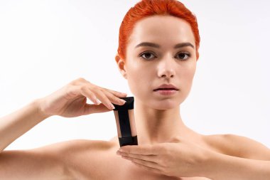 Canlı kızıl saçlı güzel bir kadın makyaj malzemesi sunar, ışık saçan bir tarz ve cazibe..